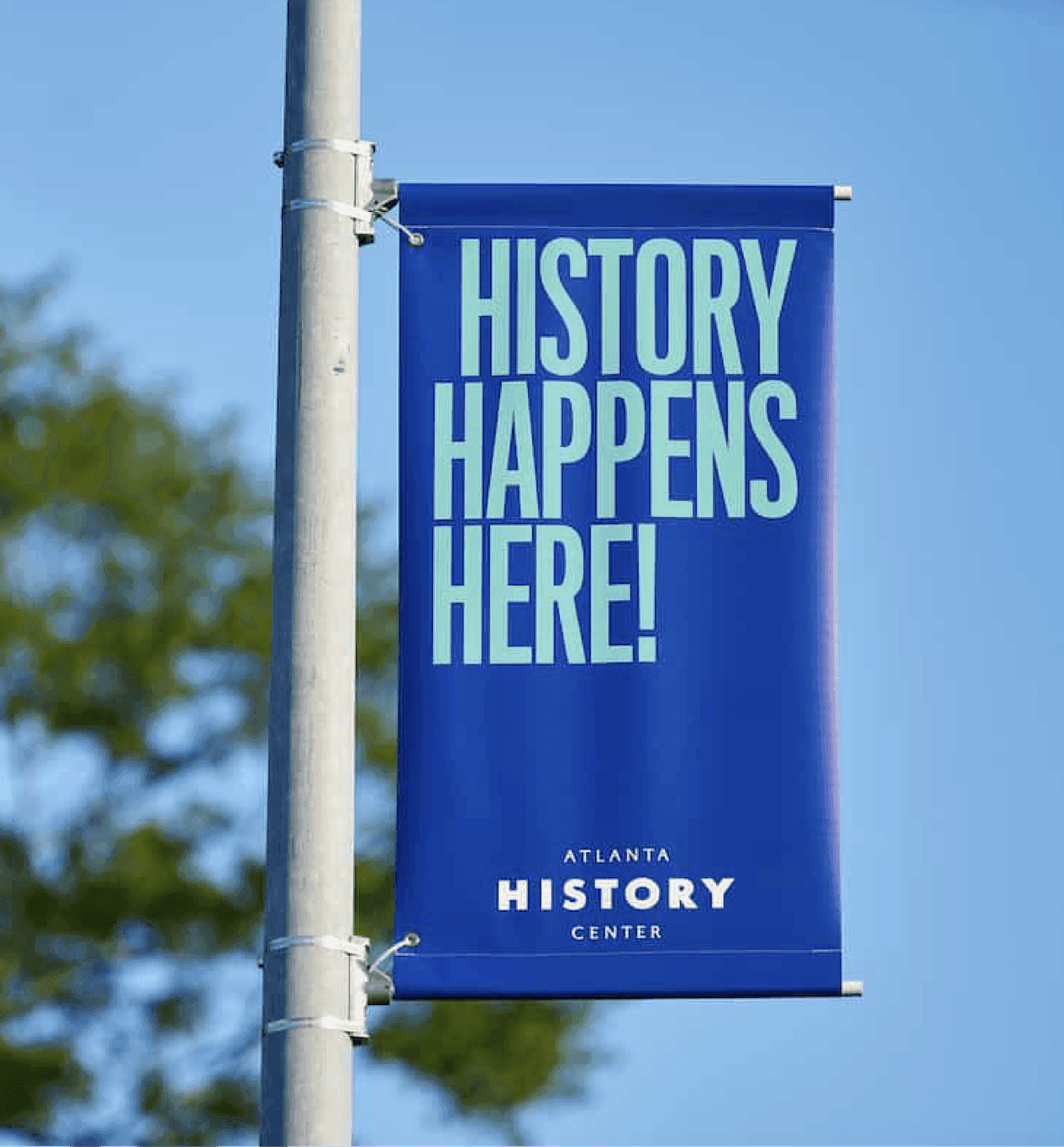An Atlanta History Center outdoor banner reading “History Happens Here,” promoting the museum’s mission to celebrate Atlanta’s stories.
