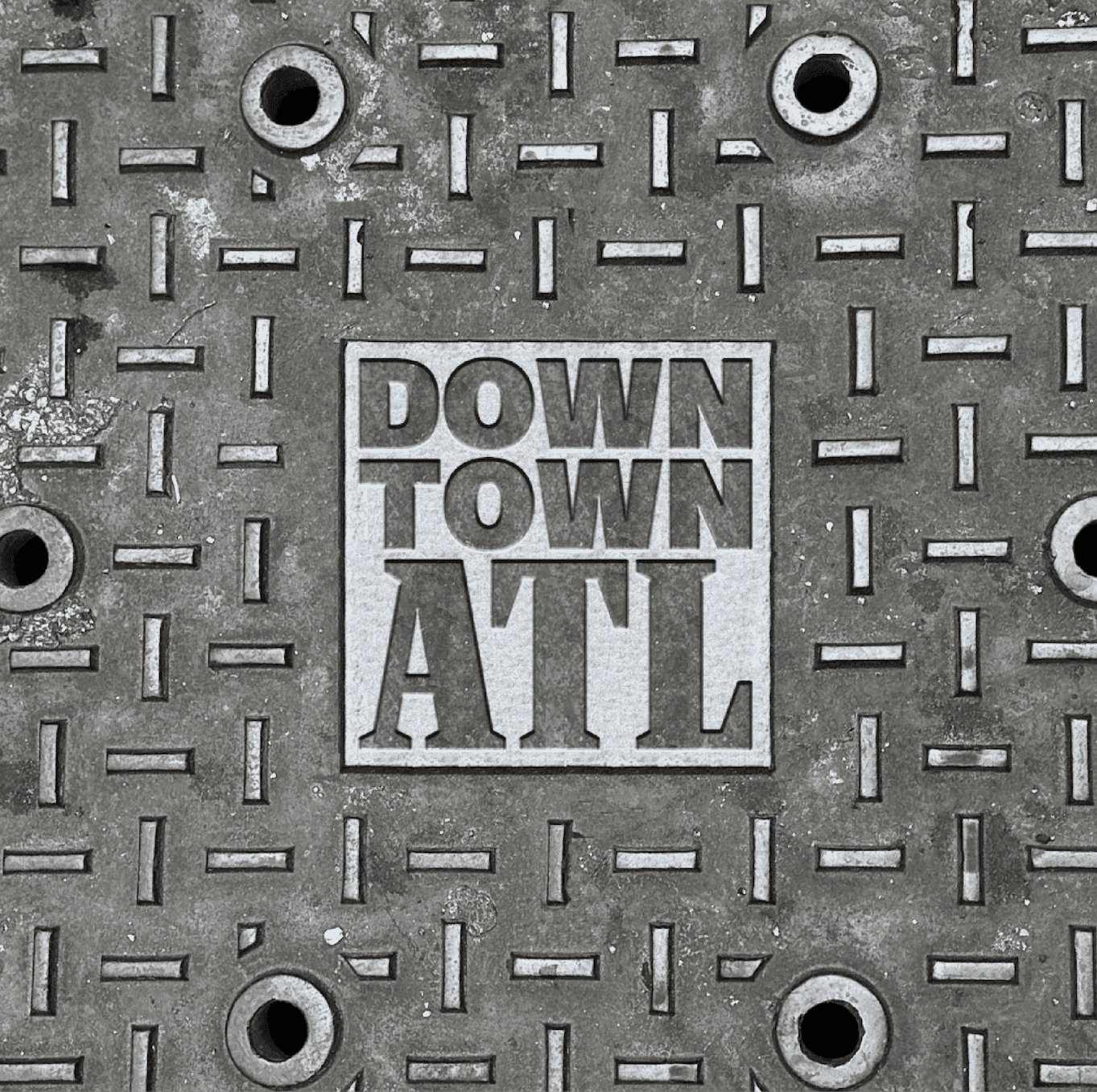 Downtown ATL Manhole Cover Mark. The Downtown ATL logo appears engraved into a textured metal manhole cover.