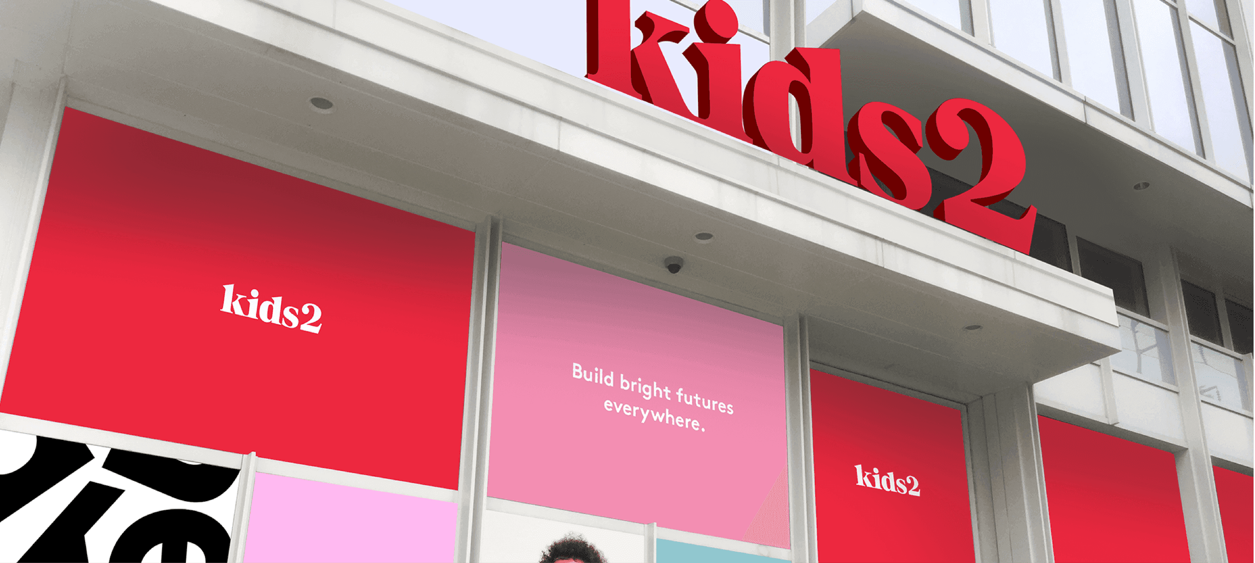 Kids2 Exterior Branding. The Kids2 headquarters exterior features bold red branding and inspirational messaging to create an inviting, modern presence.