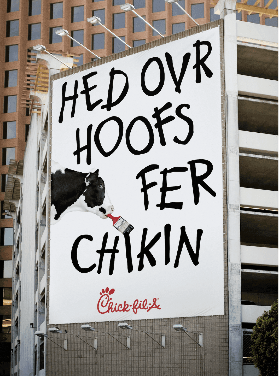 Painted Cow Billboard. A giant billboard showing a cow painting a humorous, misspelled message: “Hed Ovr Hoofs Fer Chikin.”