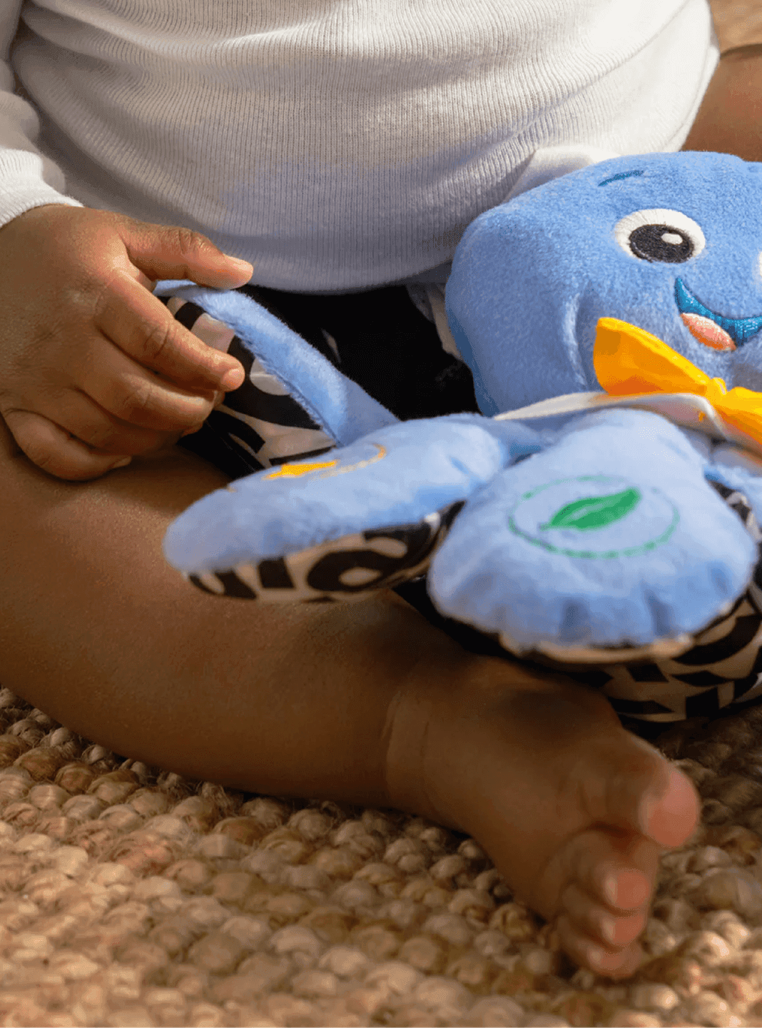 Baby Einstein sensory plush toy. A baby plays with a Baby Einstein blue plush toy featuring high-contrast patterned wings for early sensory development.